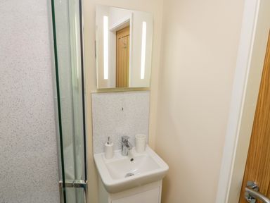 A bathroom sink with a mirror soap dispenser and toothbrush holder at Ryedale Country Lodges - Willow Lodge in Kirkbymoorside