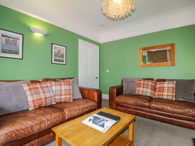 A living room with two brown leather sofas and a wooden coffee table at Sefton House in Keswick