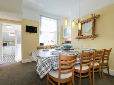 A dining room with a table covered by a checkered tablecloth and wooden chairs at Sefton House in Keswick