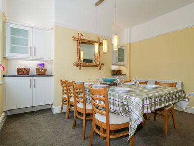 A dining room with a table covered with a plaid tablecloth and wooden chairs at Sefton House in Keswick