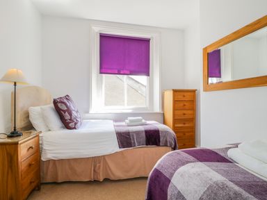 A bedroom with two single beds side by side with a purple blind on the window at Sefton House in Keswick