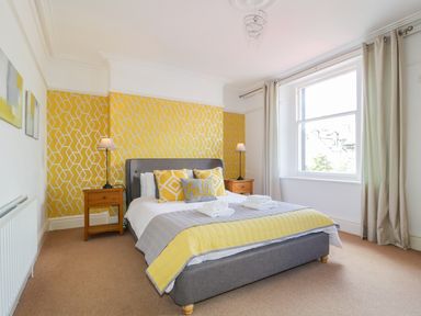 A bedroom with a bed and yellow patterned wall at Sefton House in Keswick