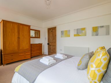 A bedroom with a bed and wooden wardrobe and dresser with a mirror at Sefton House in Keswick