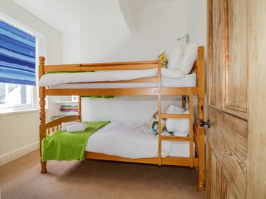 A bedroom with a wooden bunk bed two beds with white bedding and green blankets blue striped window blind at Sefton House Keswick