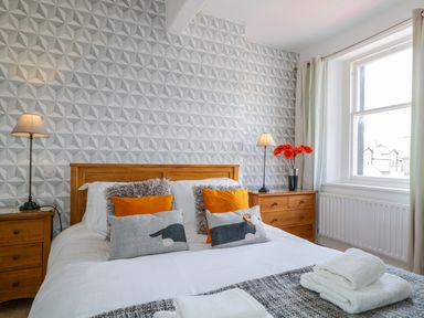 A bedroom with a wooden bed and bedside tables with lamps and orange flowers at Sefton House in Keswick