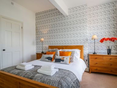 A bedroom with a wooden bed and dresser two bedside tables with lamps and decorative pillows at Sefton House in Keswick