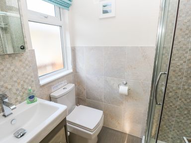 A bathroom with a sink, toilet, window, and a glass shower enclosure at Serendipity - Heritage Park in Stepaside near Kilgetty
