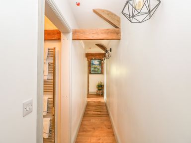 A narrow hallway with wooden beams on the ceiling and hardwood floor at The Old Farm Shop in Narberth