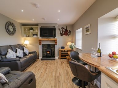 A living room with a fireplace television leather sofas and a wooden dining table at Lough Island Reavy Cottage Kilcoo Mourne Mountains Newry County Down