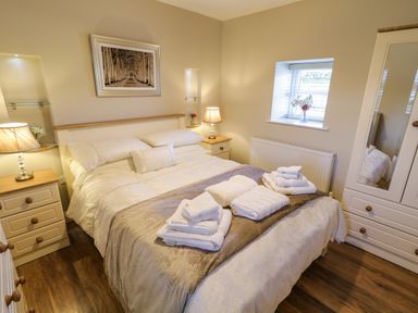 A bedroom with a double bed and folded towels on it at Lough Island Reavy Cottage in Kilcoo Mourne Mountains Newry County Down