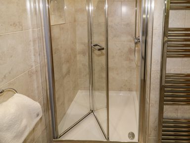A shower enclosure with glass doors and metal frame in a tiled bathroom at Lough Island Reavy Cottage Kilcoo Mourne Mountains Newry County Down