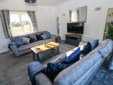 A living room with two sofas cushions a coffee table a television and curtains at The Old Well Bungalow - Ty Mawr Farm Cardiff