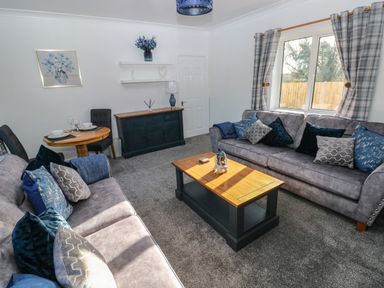A living room with two sofas a wooden coffee table a sideboard and a dining table with chairs at The Old Well Bungalow - Ty Mawr Farm Cardiff