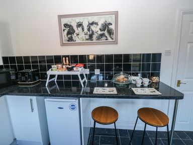 A kitchen counter with snacks mugs and two wooden stools at The Old Well Bungalow - Ty Mawr Farm in Cardiff