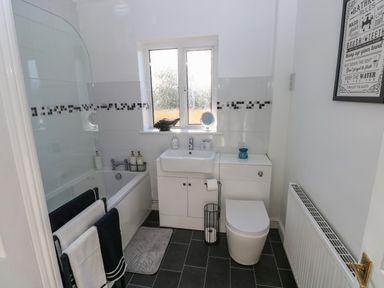 A bathroom with a bathtub sink toilet and radiator with a window above the sink at The Old Well Bungalow - Ty Mawr Farm in Cardiff