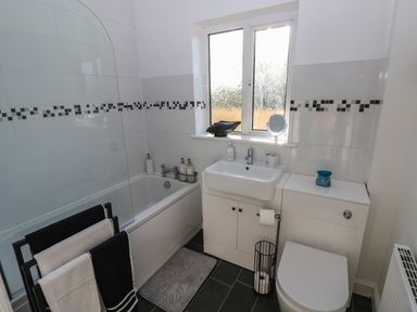 A bathroom with a bathtub toilet sink and tiled walls at The Old Well Bungalow - Ty Mawr Farm Cardiff