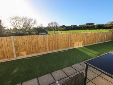 A backyard with a wooden fence green grass and patio furniture at The Old Well Bungalow - Ty Mawr Farm in Cardiff