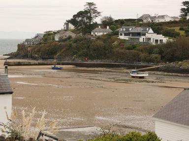 A coastal scene with boats on sand and houses on a hill at Castell in Abersoch