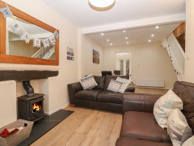 A living room with two leather sofas a wood burning stove and a large wall mirror at Castell in Abersoch