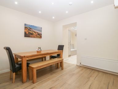 A dining room with a wooden table bench and two chairs and a wall painting at Castell in Abersoch