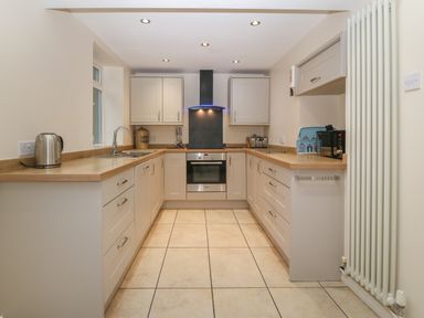 A kitchen with cabinets oven stovetop kettle and microwave at Castell in Abersoch