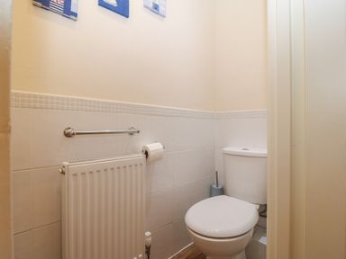 A small bathroom with a toilet radiator toilet paper holder and wall decorations at Castell in Abersoch