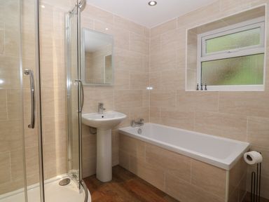 A bathroom with a shower enclosure sink bathtub and frosted window at Castell in Abersoch