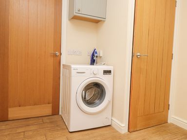 A laundry area with a washing machine and an iron between two wooden doors at The Cottage in Llaniestyn