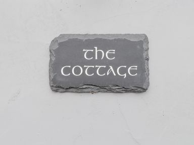 A stone plaque with the text the cottage on a white wall at The Cottage in Llaniestyn