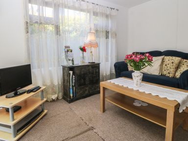 A living room with a sofa and a coffee table at Castell Chalet in Penrhos near Pwllheli
