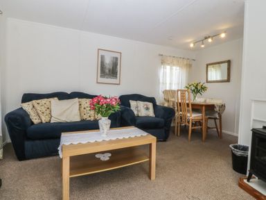 A living room with a sofa and dining table at Castell Chalet in Penrhos near Pwllheli