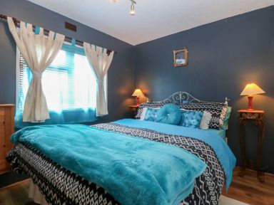 A bedroom with a bed and bedside tables with lamps at Castell Chalet Penrhos near Pwllheli