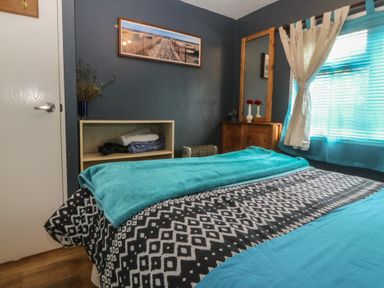 A bedroom with a bed, shelves, and window at Castell Chalet in Penrhos near Pwllheli