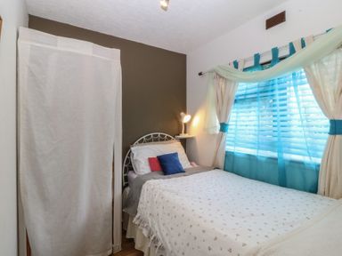 A bedroom with a bed, lamp, and window at Castell Chalet in Penrhos near Pwllheli