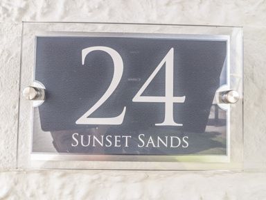 A house number sign with 24 and sunset sands on a textured wall at Sunset Sands in Deganwy