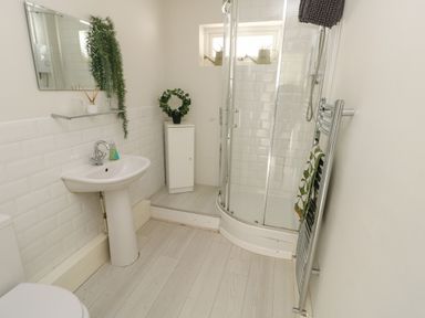 A bathroom with a sink mirror shower enclosure and towel rail at Sunset Sands in Deganwy