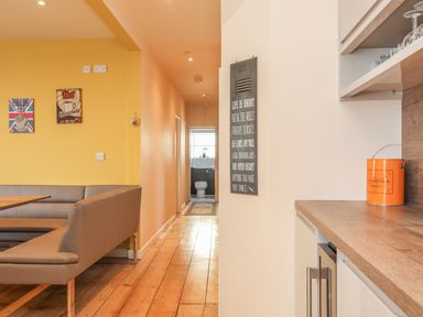 A dining area with a corner bench and table next to a hallway leading to a bathroom at Gadlys House Waters Edge in Beaumaris