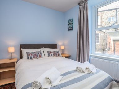 A bedroom with a bed lamps on bedside tables and a window at Gadlys House - Waters Edge in Beaumaris