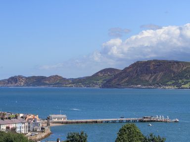 A coastal town with houses near a pier and mountains in the background at Gadlys House Waters Edge Beaumaris