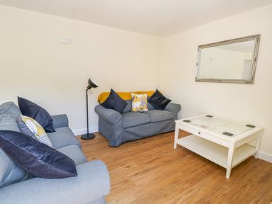 A living room with two blue sofas a white coffee table and a wall mirror at Puddleducks in Sherborne