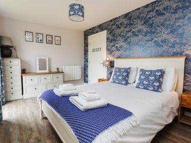 A bedroom with a bed and decorative wall at Cowslip in Bamburgh