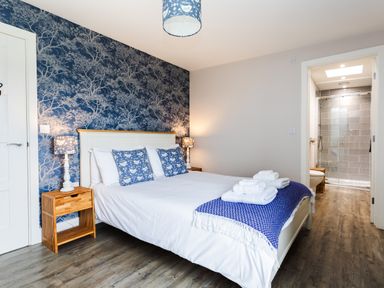 A bedroom with a bed and en suite bathroom at Cowslip in Bamburgh