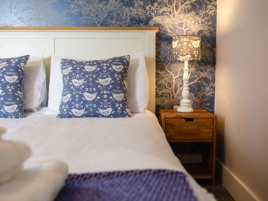 A bedroom with pillows and a lamp on a nightstand at Cowslip in Bamburgh