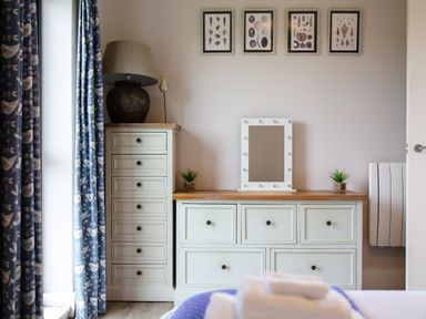 A bedroom with a dresser and mirror at Cowslip in Bamburgh