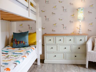 A bedroom with a bunk bed and a dresser at Cowslip in Bamburgh
