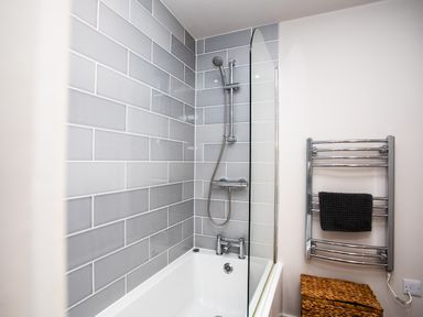 A bathroom with a bathtub and shower feature at Cowslip in Bamburgh