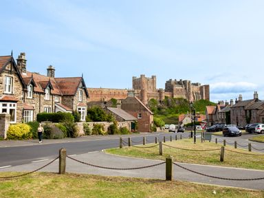 A street view with houses and a castle in the background at Cowslip Bamburgh