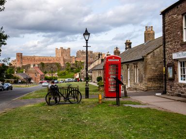 A street scene featuring a castle and a telephone box at Cowslip in Bamburgh