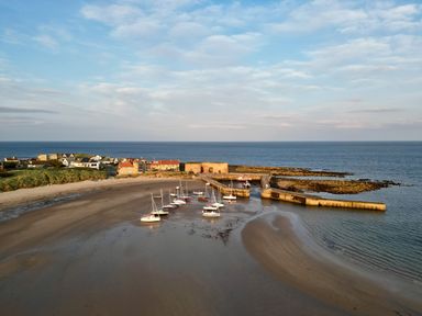 A coastal view with boats at a pier and houses at Cowslip in Bamburgh