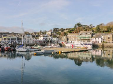 A harbor with boats docked near buildings and a floating platform on calm water at Sunflower Cottage in St Issey